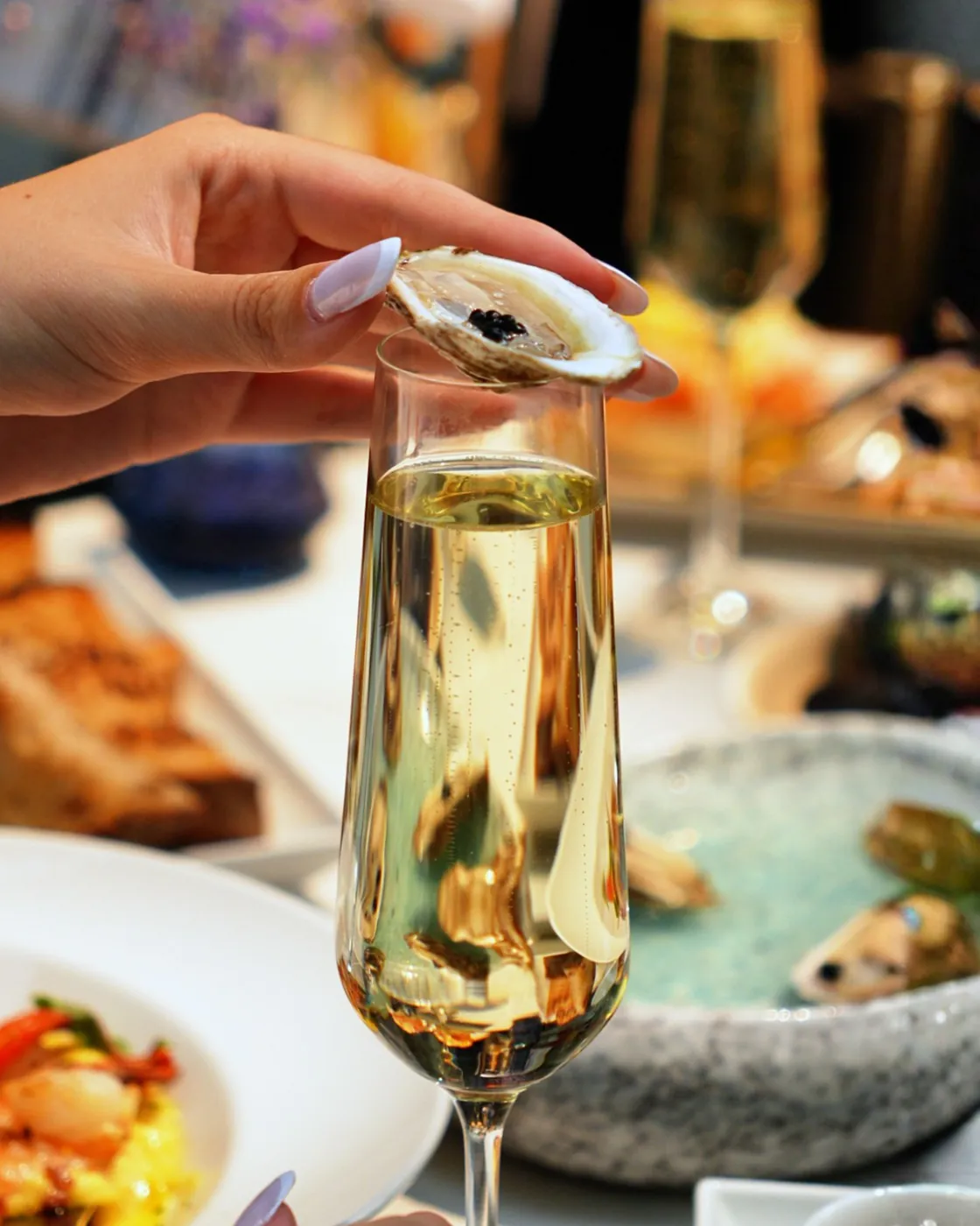 Oyster with caviar balanced on a champagne flute